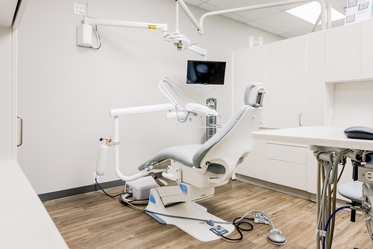 A dental treatment room, with the chair, overhead light and instrument tray ready for the next patient.